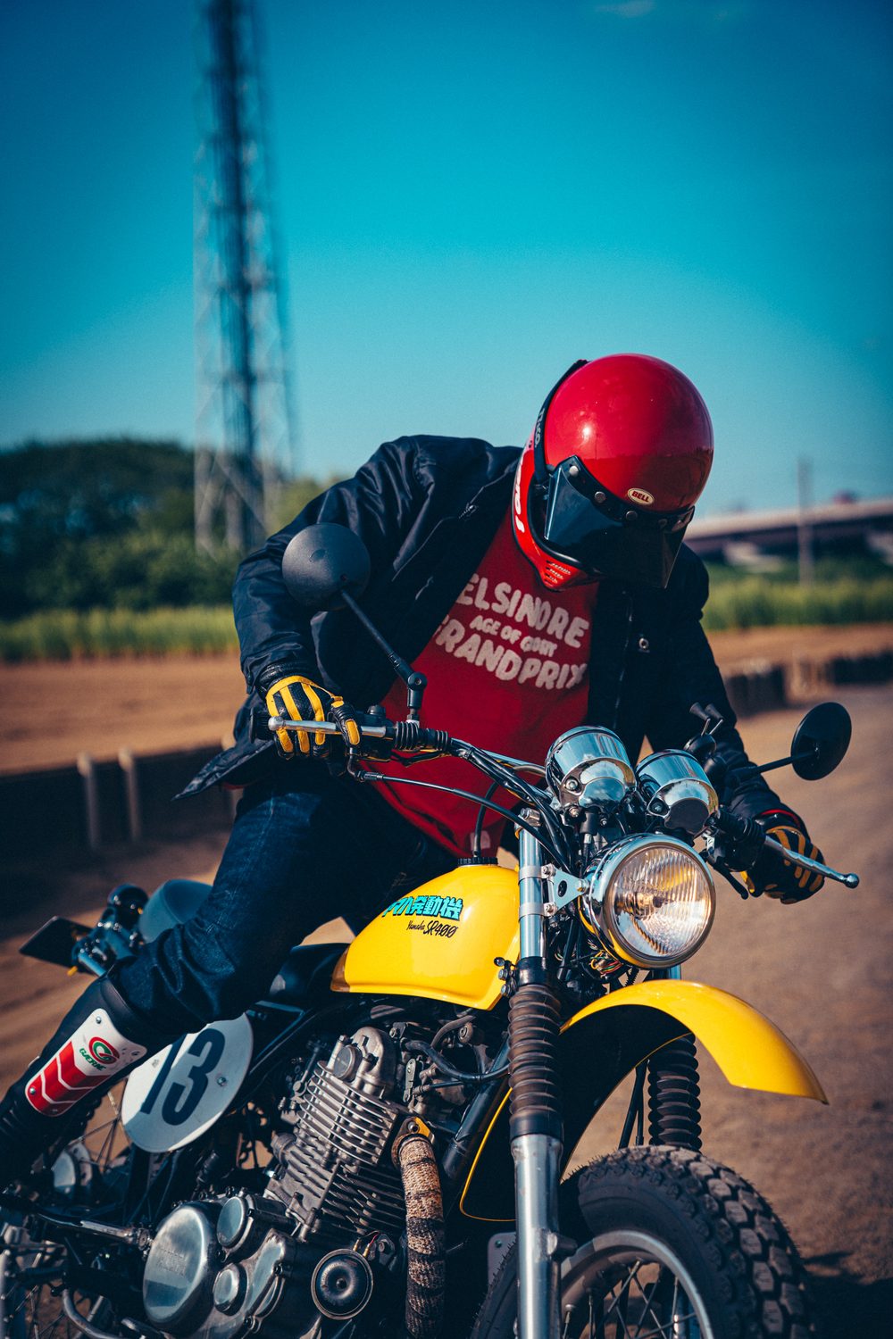 VMXバーと丸型ヘッドライトを装着したSR400に跨り、ハンドルを握るライダー