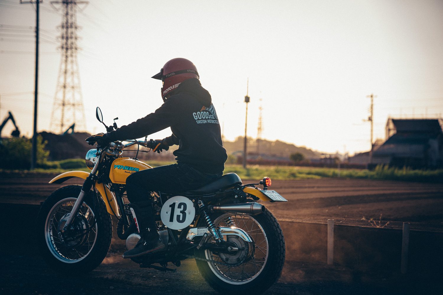 夕日を背にSR400に跨るライダーと、車体左側のアップマフラーや13番のゼッケン