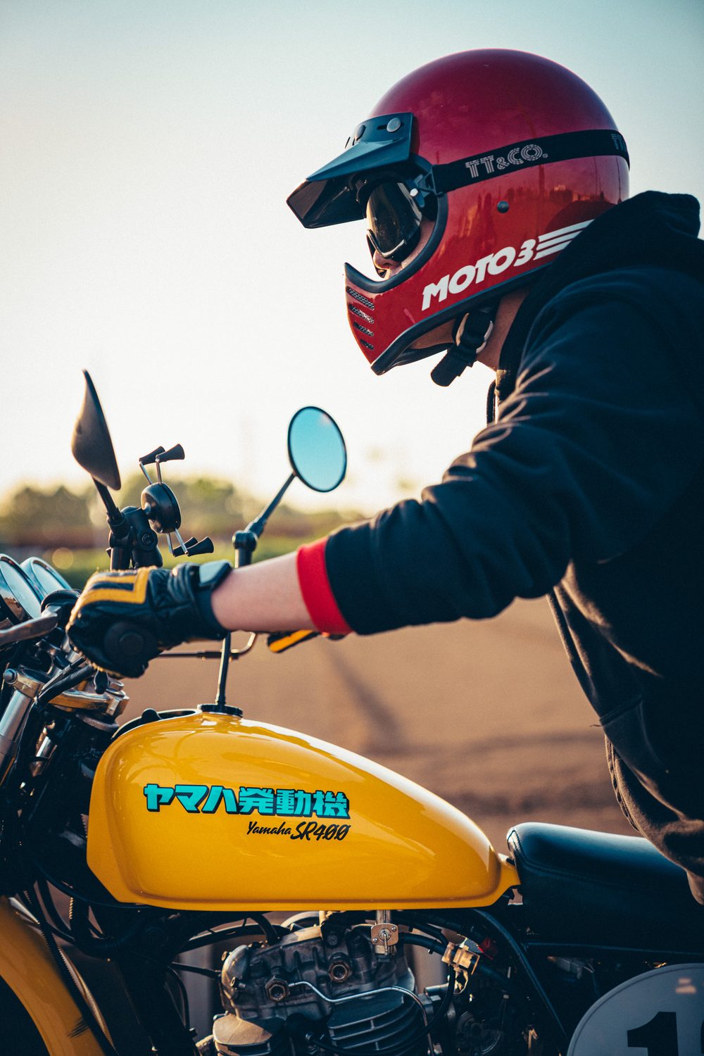 赤いBELL MOTO-3をかぶり、黄色いMXタンクのSR400に跨るライダー