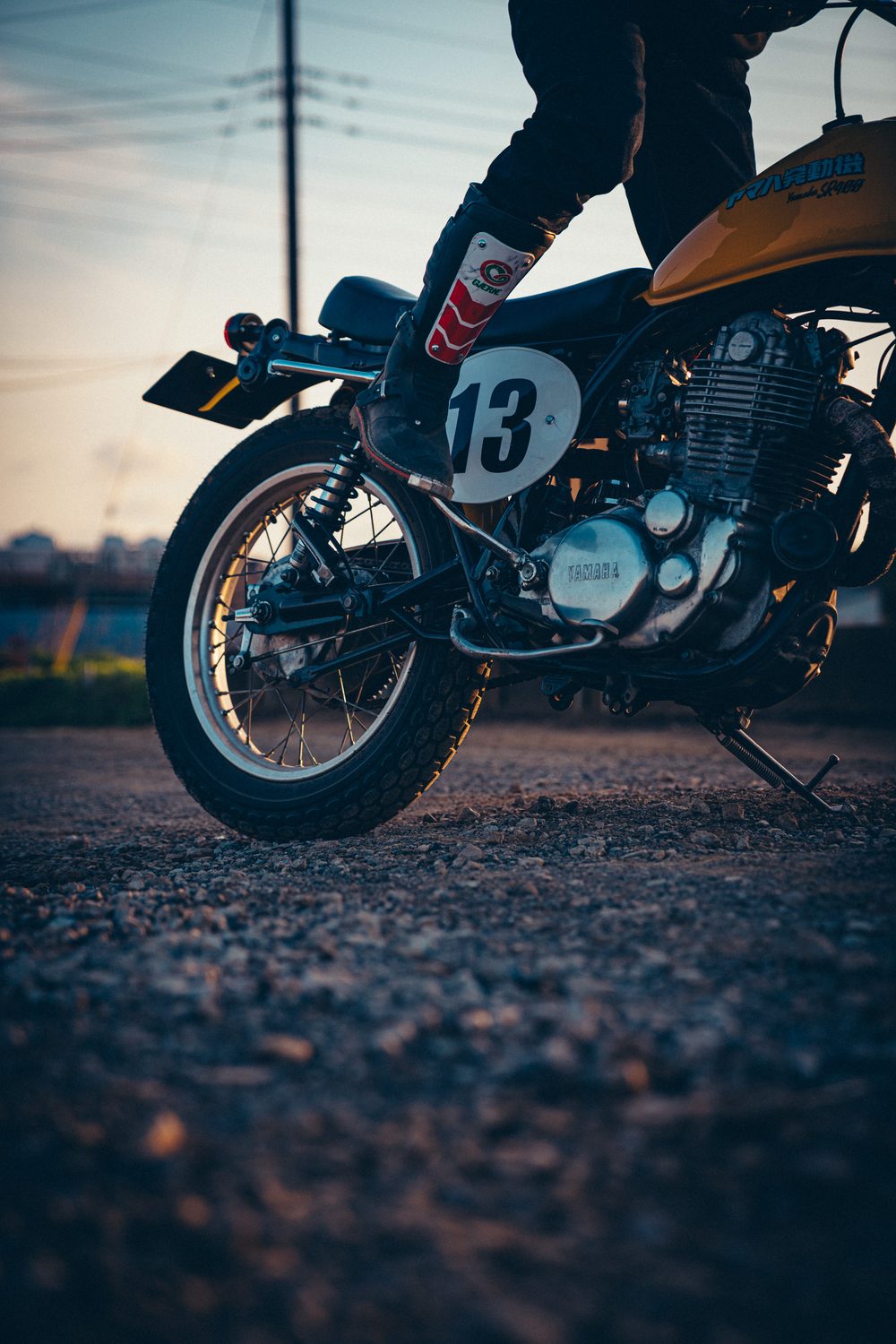 13番のゼッケンと空冷単気筒エンジンが見える、SR400のキック始動時の足元