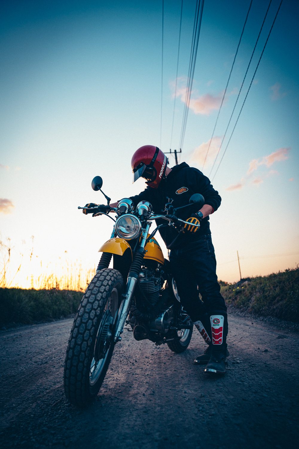 夕暮れのダートで、スクランブラーカスタムのSR400のハンドルを握るライダー