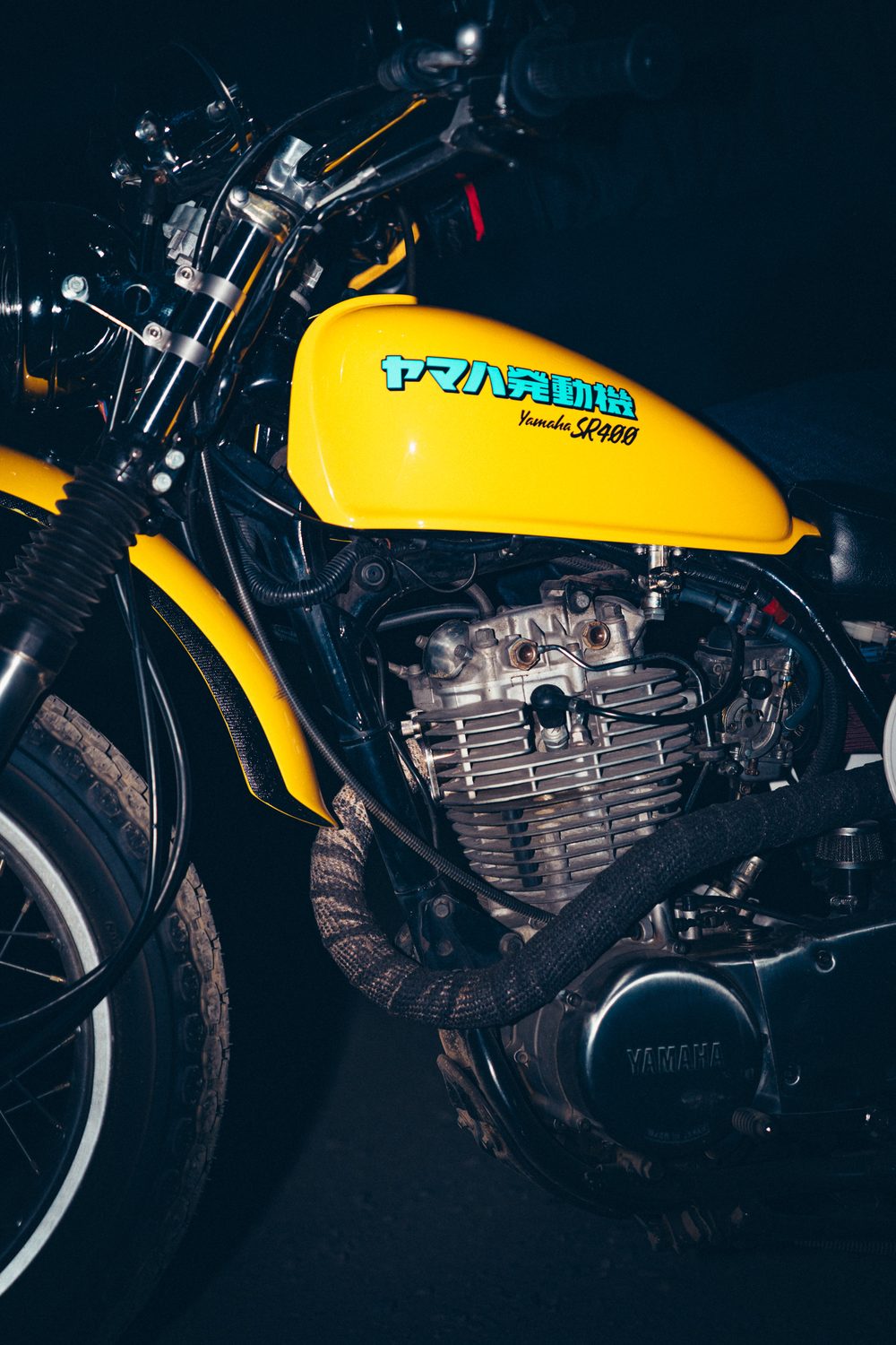 黄色いMXタンクと、バンテージを巻いたアップマフラーが見えるSR400のエンジン周り